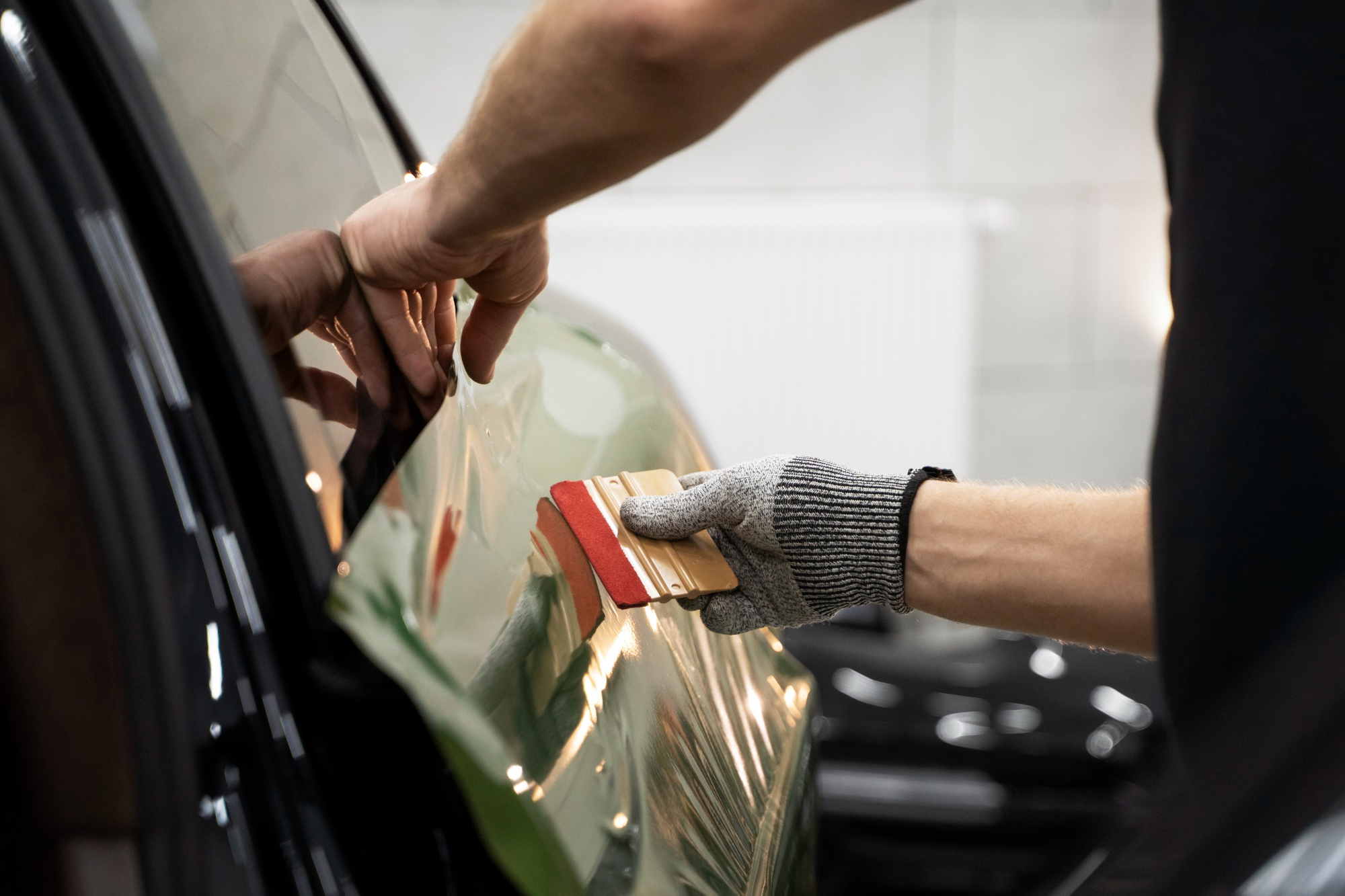 Technician applying paint protection film to a car for added protection and shine.