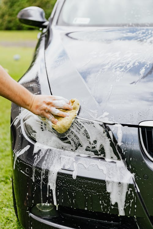 Person cleaning a black car after paint protection film installation.