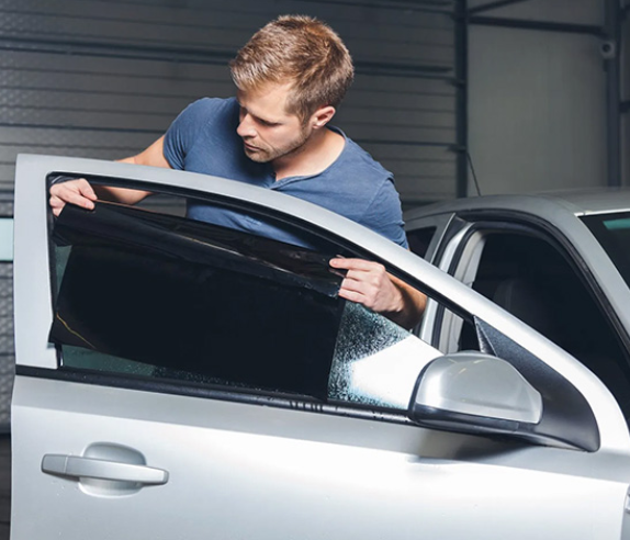  Technician applying window tint to a car, representing automotive tinting benefits for fleets