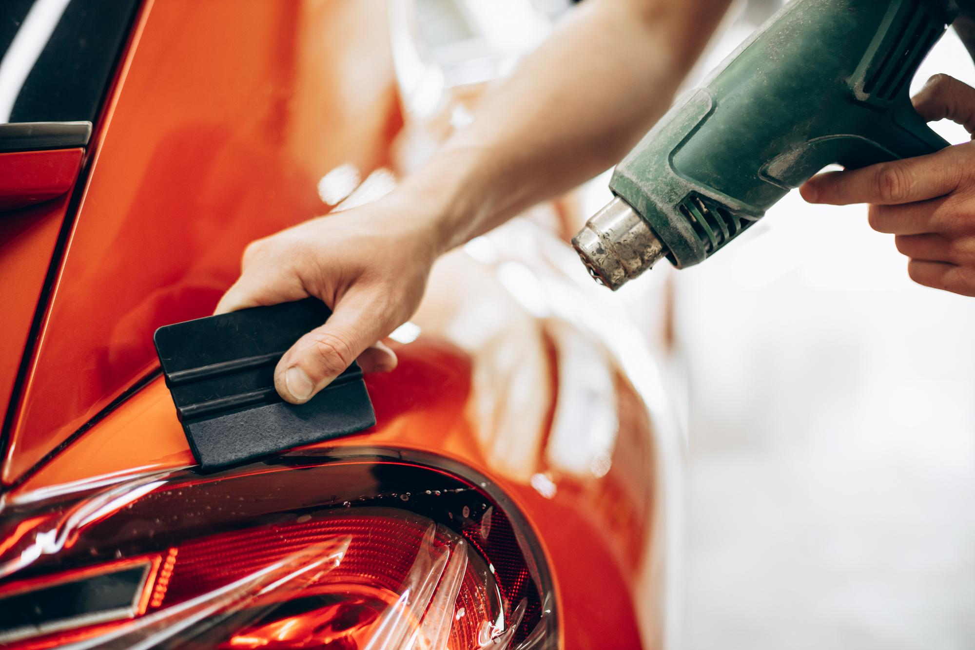 Technician drying paint protection film with a fan for a flawless finish and longevity.