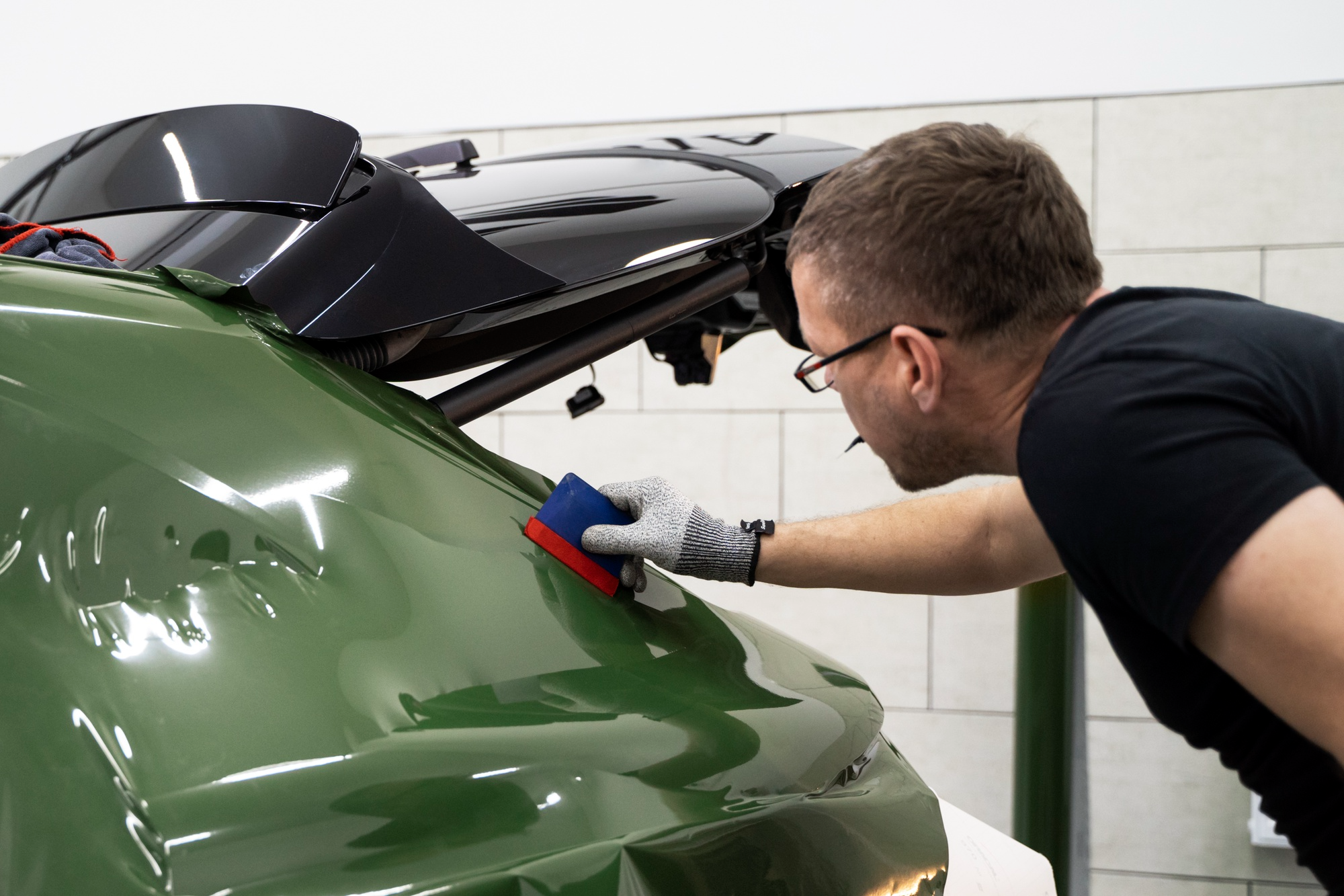 Technician applying PPF (paint protection film) to a vehicle’s surface with precision and care.
