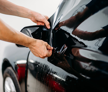 Window tint being professionally applied to a high-end car inside a clean garage