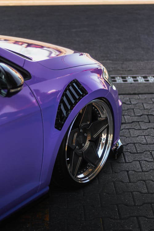 Close-up of a car’s front wheel with a violet vinyl wrap finish.