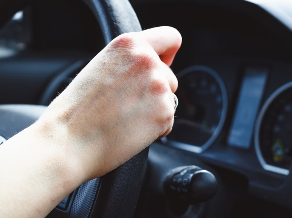 This image shows a person is driving a car in broad daylight. 