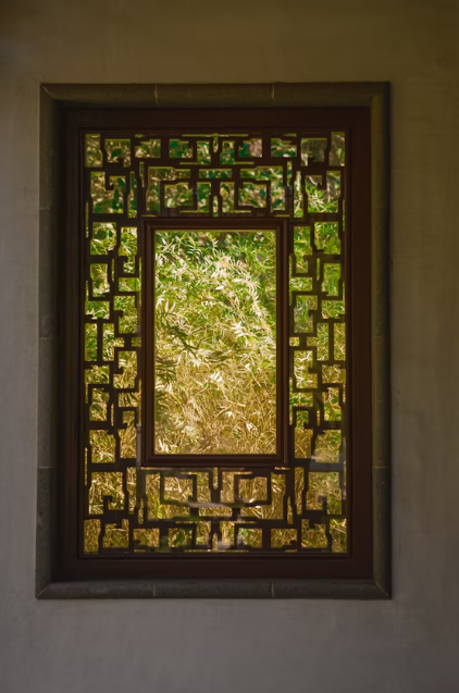 This image shows a decorative window on wall with tree in background.