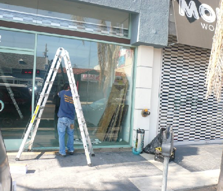 Expert carefully installing anti-graffiti window film to protect a Venice Beach storefront and preserve its brand image.