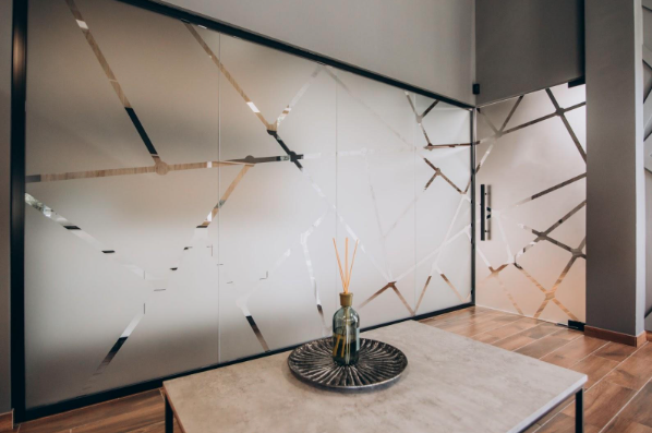 Interior glass partition with decorative frosted window film in office setting.