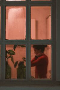 silhouette of a woman through a window with warm indoor light