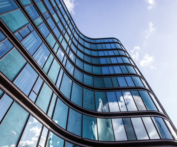 high rise building glass facade with reflection surrounding buildings